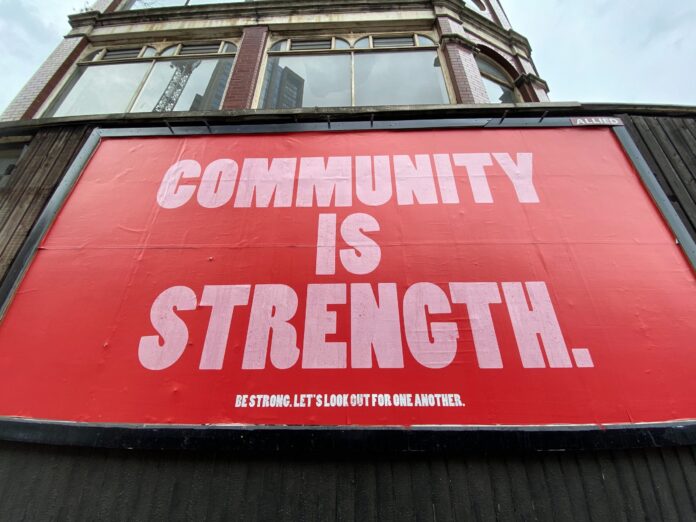 Community is strength written on a red city billboard